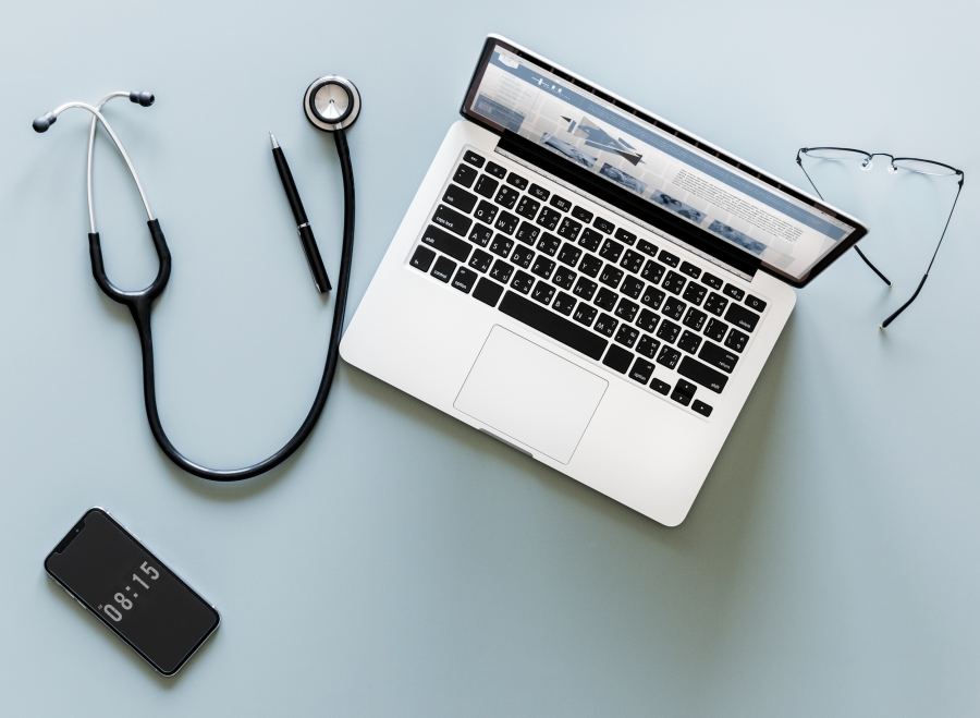 Photo of doctor's stethoscope, laptop, and pair of eye glasses
